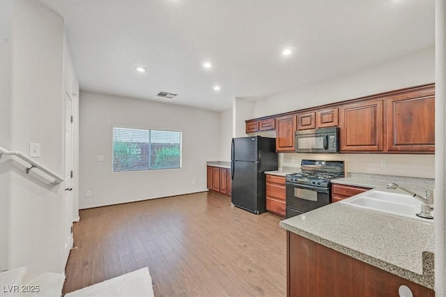 kitchen featuring light countertops, brown cabinets, black appliances, a sink, and visible vents