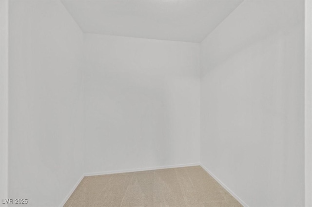 empty room featuring baseboards and light carpet