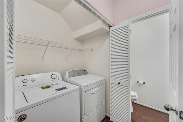 clothes washing area with dark wood finished floors, baseboards, laundry area, and washing machine and dryer