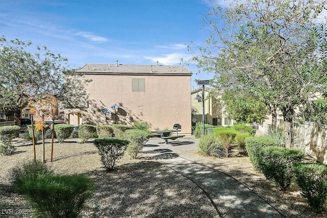 rear view of property with fence, stucco siding, and a patio area