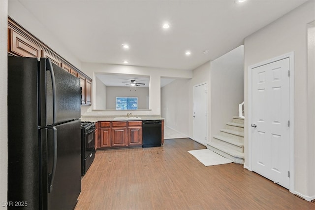 kitchen with recessed lighting, a sink, light wood-type flooring, black appliances, and light countertops
