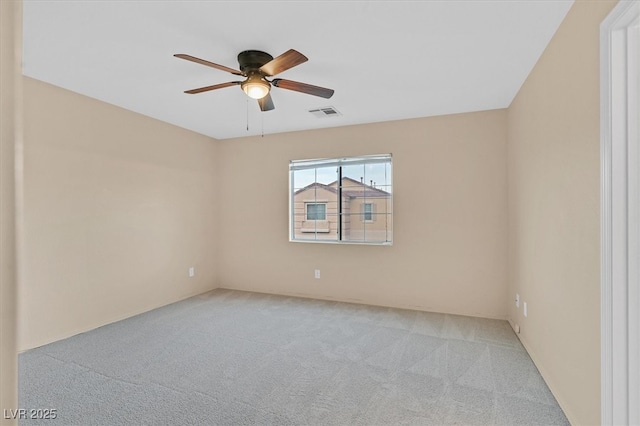 carpeted spare room featuring a ceiling fan and visible vents