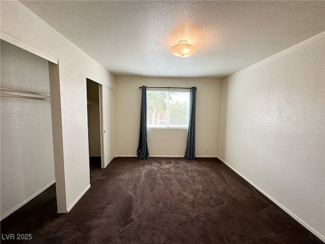 unfurnished bedroom with a textured wall, carpet flooring, multiple closets, and a textured ceiling