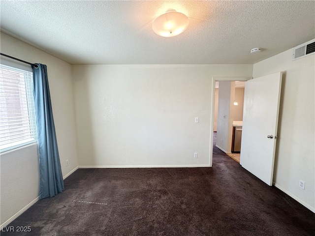 empty room with baseboards, visible vents, carpet floors, and a textured ceiling