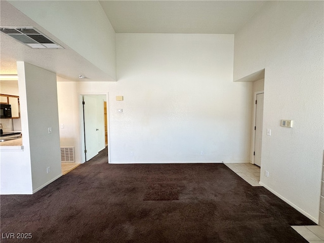 spare room featuring carpet, visible vents, and baseboards