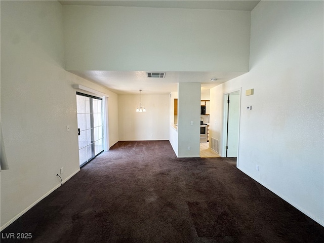 empty room with baseboards, visible vents, dark carpet, and a notable chandelier