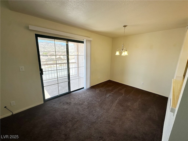 spare room with dark colored carpet, baseboards, a textured ceiling, and a notable chandelier