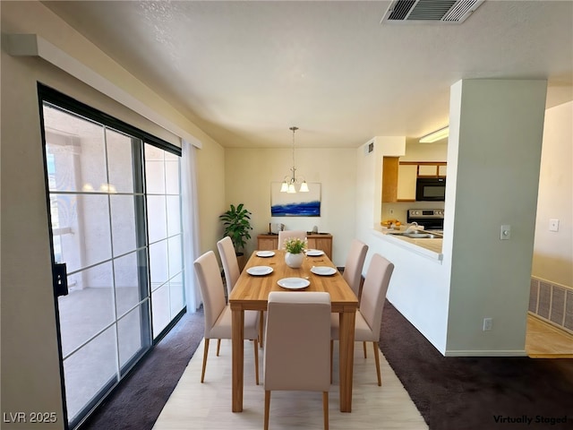 dining space with a chandelier, wood finished floors, and visible vents