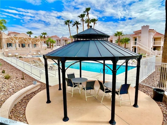 view of pool with fence, a gazebo, a residential view, and a patio