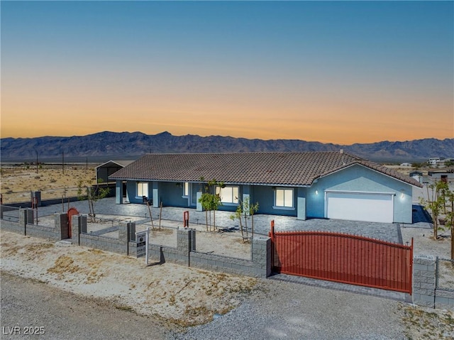 view of front of house featuring a garage, a fenced front yard, a mountain view, and a tiled roof