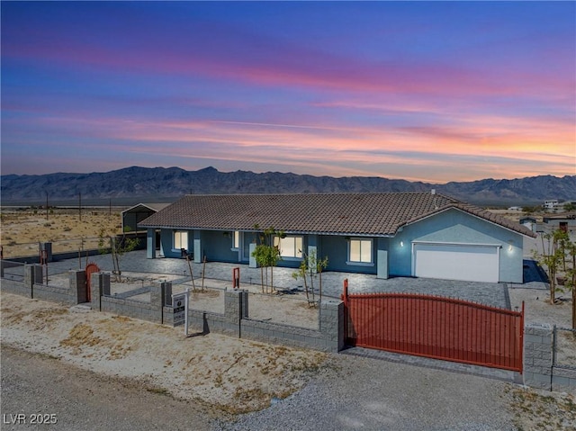 view of front of house featuring a tiled roof, an attached garage, a fenced front yard, and a mountain view