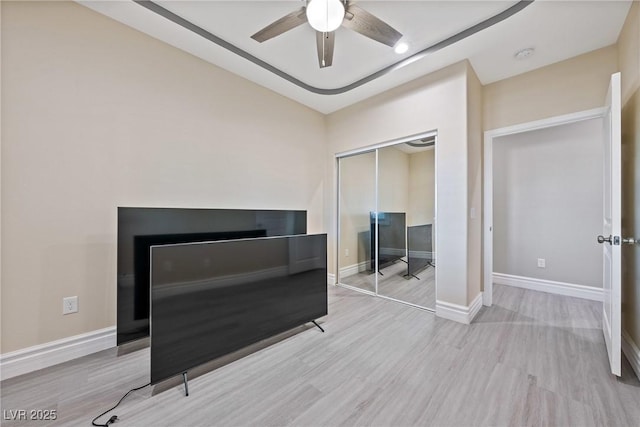 unfurnished bedroom with baseboards, a ceiling fan, wood finished floors, and a closet