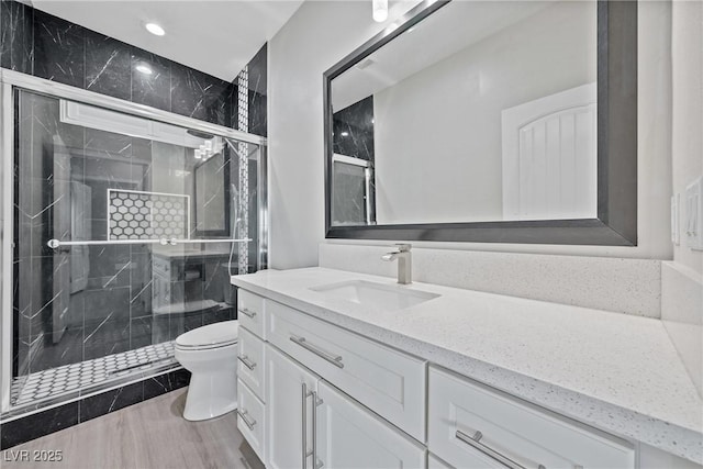 bathroom featuring recessed lighting, vanity, a stall shower, and toilet