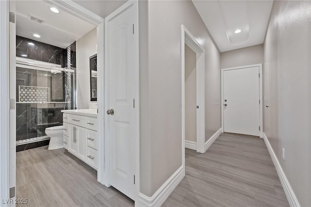 corridor with baseboards, visible vents, and light wood-type flooring
