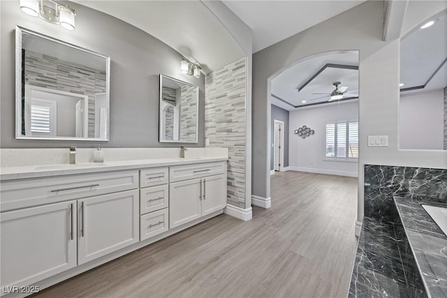 full bath featuring double vanity, baseboards, a ceiling fan, and a sink
