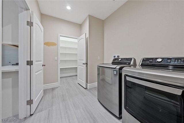 clothes washing area with light wood-type flooring, baseboards, and washer and dryer