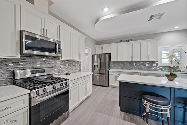 kitchen with stainless steel appliances, visible vents, white cabinetry, and tasteful backsplash