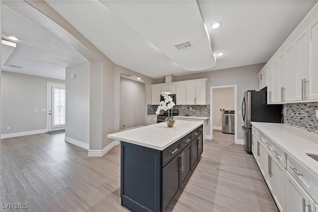 kitchen with visible vents, light countertops, white cabinetry, and a kitchen island