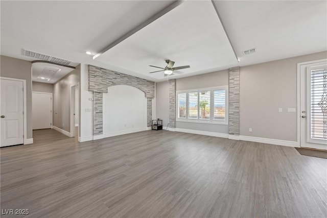 unfurnished living room featuring baseboards, ceiling fan, visible vents, and wood finished floors