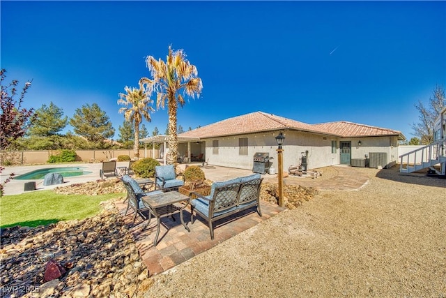 rear view of property with stucco siding, fence, a tiled roof, a fenced in pool, and a patio area