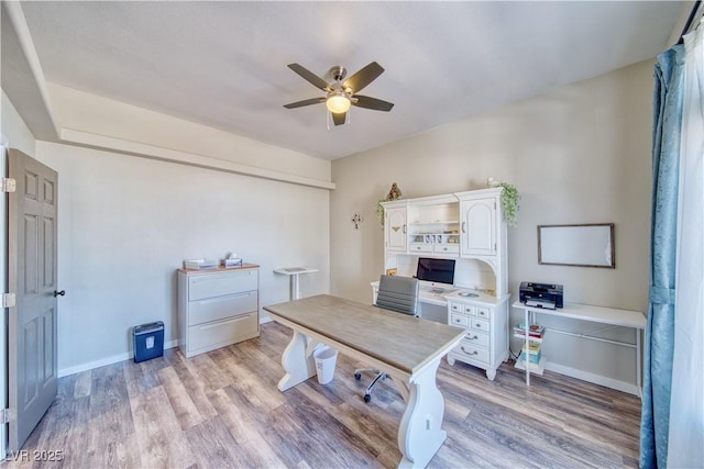 office space with baseboards, ceiling fan, and light wood-style floors