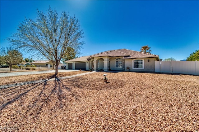 mediterranean / spanish-style house with stucco siding, driveway, a garage, and fence