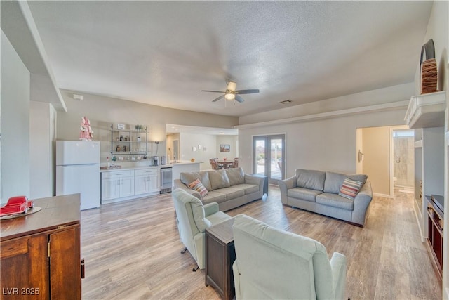 living area featuring a textured ceiling, visible vents, ceiling fan, wine cooler, and light wood-type flooring