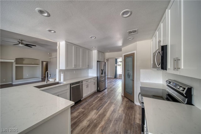 1131 China St, Pahrump, NV 89048 - kitchen featuring a sink, appliances with stainless steel finishes, a textured ceiling, white cabinetry, and dark wood-style flooring