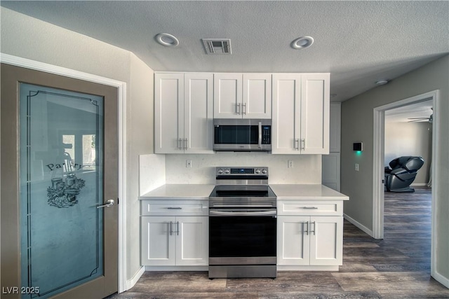 1131 China St, Pahrump, NV 89048 - kitchen featuring stainless steel appliances, light countertops, white cabinetry, dark wood-type flooring, and a textured ceiling