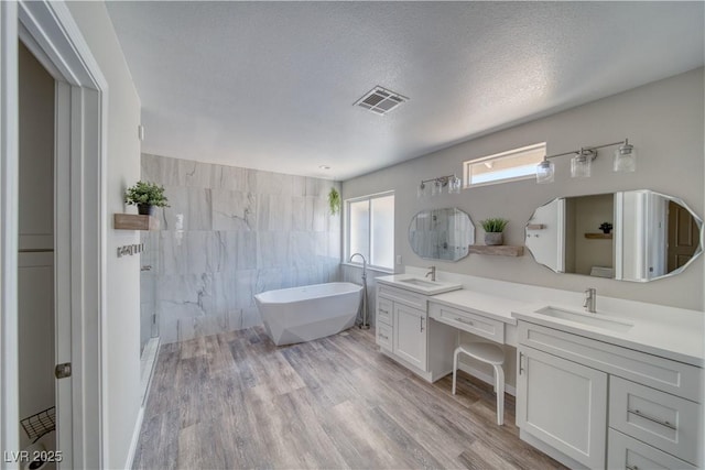1131 China St, Pahrump, NV 89048 - full bathroom with double vanity, walk in shower, a freestanding bath, and wood finished floors