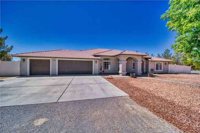1131 China St, Pahrump, NV 89048 - mediterranean / spanish-style house featuring stucco siding, an attached garage, a tiled roof, and driveway