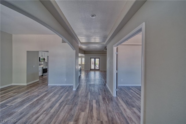 1131 China St, Pahrump, NV 89048 - entrance foyer with dark wood-style flooring, arched walkways, baseboards, a raised ceiling, and a textured ceiling