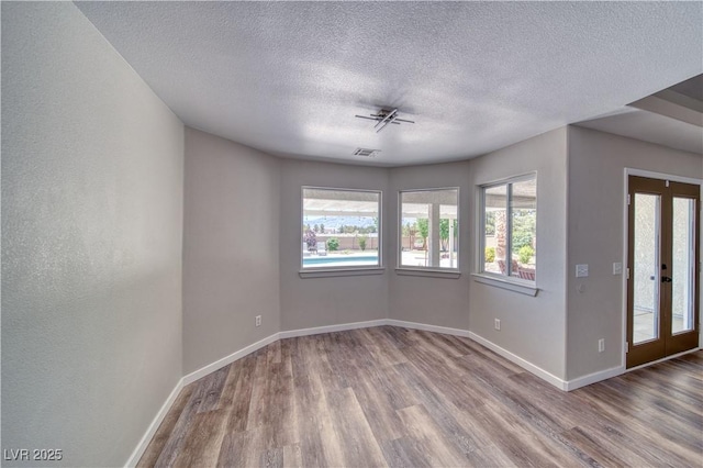 1131 China St, Pahrump, NV 89048 - empty room with wood finished floors, a textured ceiling, baseboards, french doors, and a ceiling fan