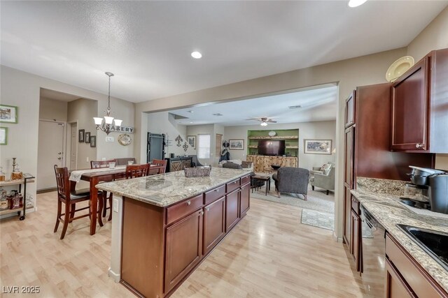 kitchen featuring a kitchen island, light wood-type flooring, ceiling fan with notable chandelier, open floor plan, and stainless steel dishwasher