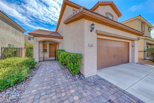exterior space with driveway, a gate, stucco siding, fence, and a garage