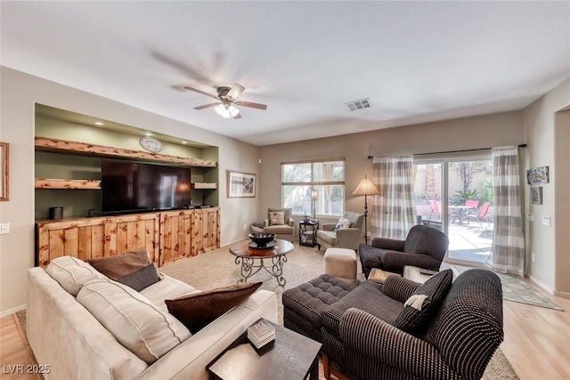 living room with baseboards, light wood-style flooring, ceiling fan, and visible vents