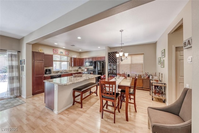 kitchen with a kitchen island, black appliances, a sink, and light wood-type flooring