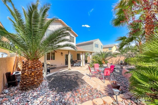 back of house with fence, outdoor dining area, a patio, and stucco siding