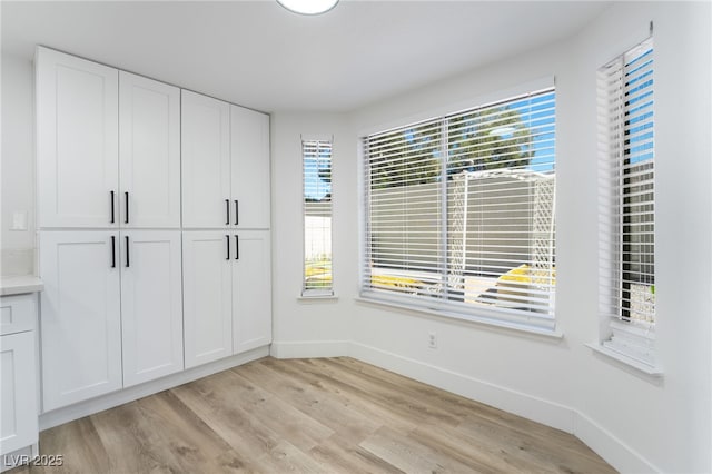 unfurnished bedroom featuring baseboards, a closet, and light wood finished floors