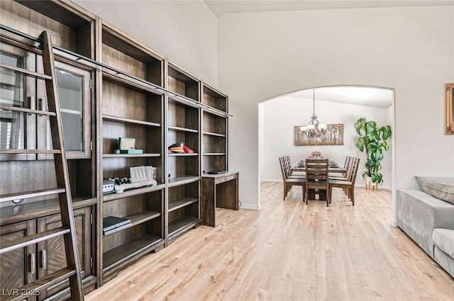 8515 Belcastro St, Las Vegas, NV 89113 - dining space featuring a chandelier, arched walkways, light wood-style flooring, and baseboards