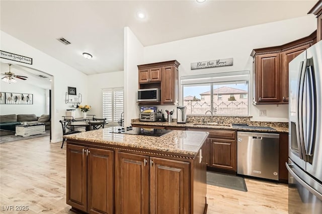 8515 Belcastro St, Las Vegas, NV 89113 - kitchen featuring appliances with stainless steel finishes, a sink, a center island, light stone countertops, and plenty of natural light