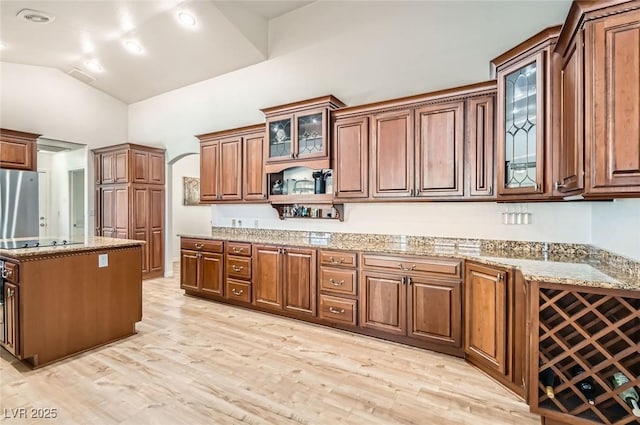 8515 Belcastro St, Las Vegas, NV 89113 - kitchen with light wood finished floors, black electric stovetop, fridge, vaulted ceiling, and light stone counters