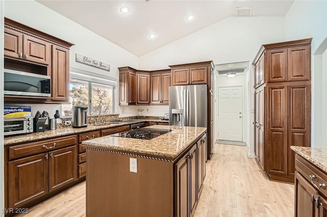 8515 Belcastro St, Las Vegas, NV 89113 - kitchen featuring appliances with stainless steel finishes, lofted ceiling, light wood-style floors, light stone counters, and a center island