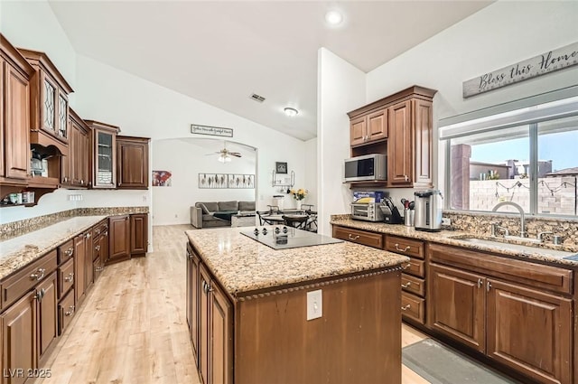 8515 Belcastro St, Las Vegas, NV 89113 - kitchen featuring a sink, black electric stovetop, stainless steel microwave, a kitchen island, and lofted ceiling