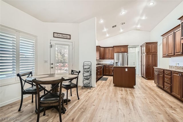 8515 Belcastro St, Las Vegas, NV 89113 - kitchen with stainless steel fridge, a center island, light wood-style floors, vaulted ceiling, and baseboards