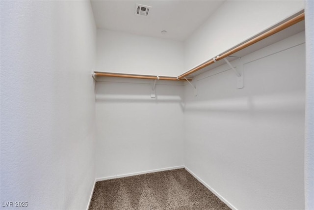 walk in closet featuring dark carpet