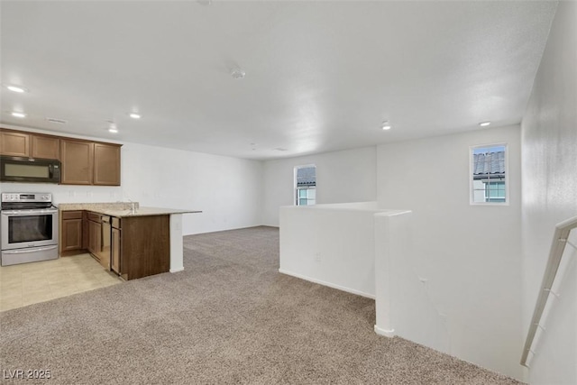 kitchen featuring stainless steel range with electric stovetop, black microwave, light colored carpet, open floor plan, and a peninsula