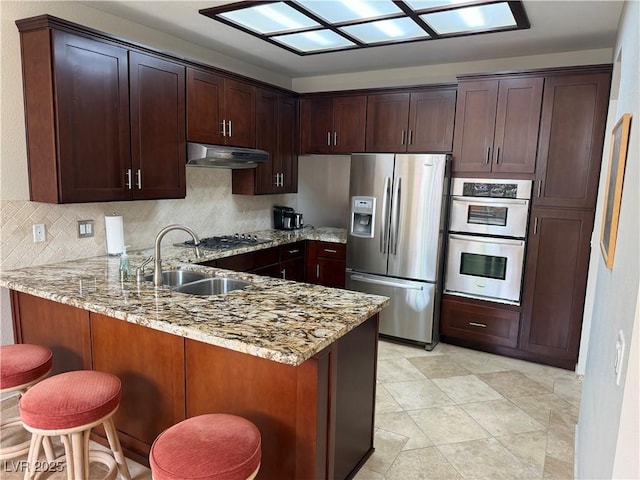 2796 Cape Hope Way, Las Vegas, NV 89121 - kitchen featuring appliances with stainless steel finishes, under cabinet range hood, a sink, a peninsula, and light stone countertops