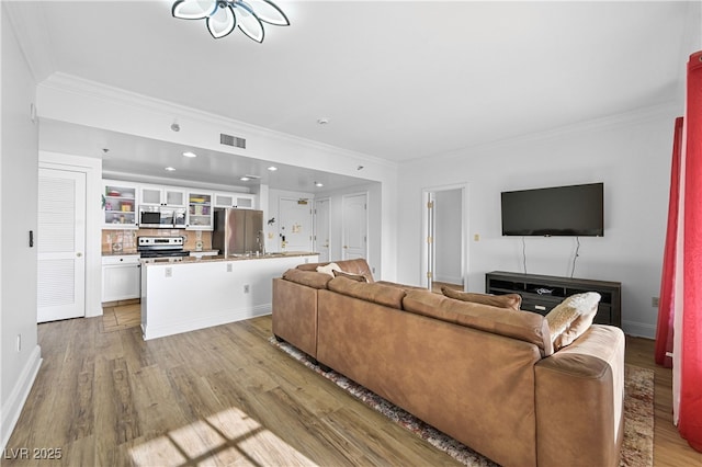 30 Strada Di Villaggio 409, Henderson, NV 89011 - living area with baseboards, crown molding, light wood-style floors, and visible vents