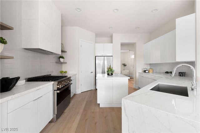 kitchen featuring a sink, stainless steel appliances, backsplash, light wood-type flooring, and a kitchen island